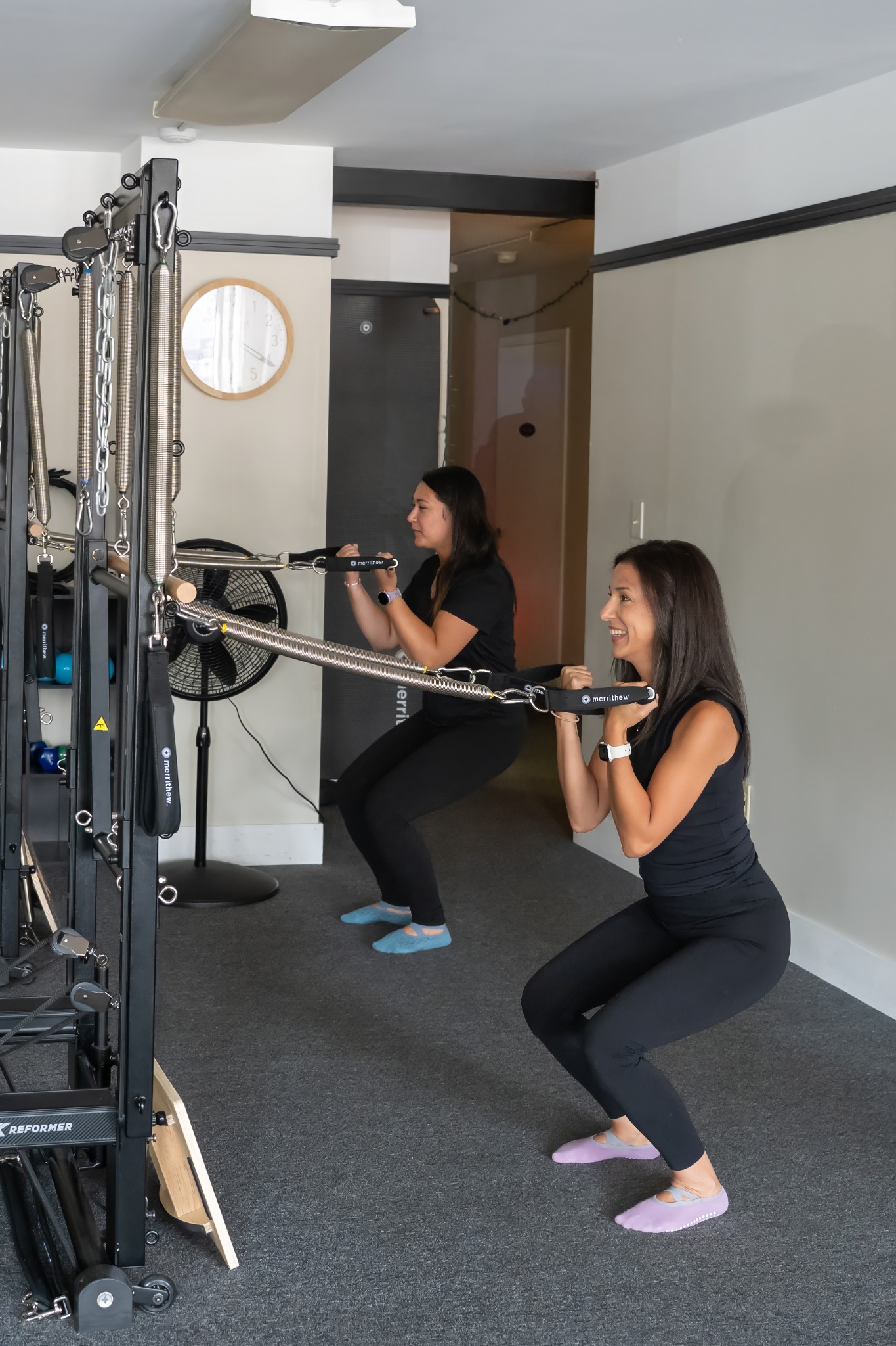 Two clients strength training with Pilates tower springs